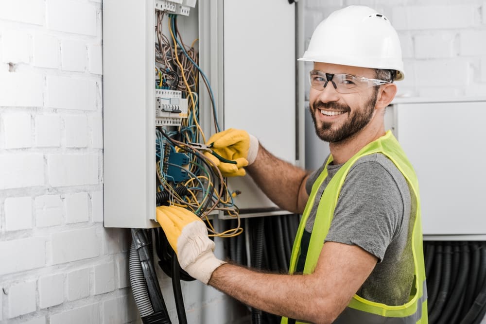 Smiling electrician working on equipment