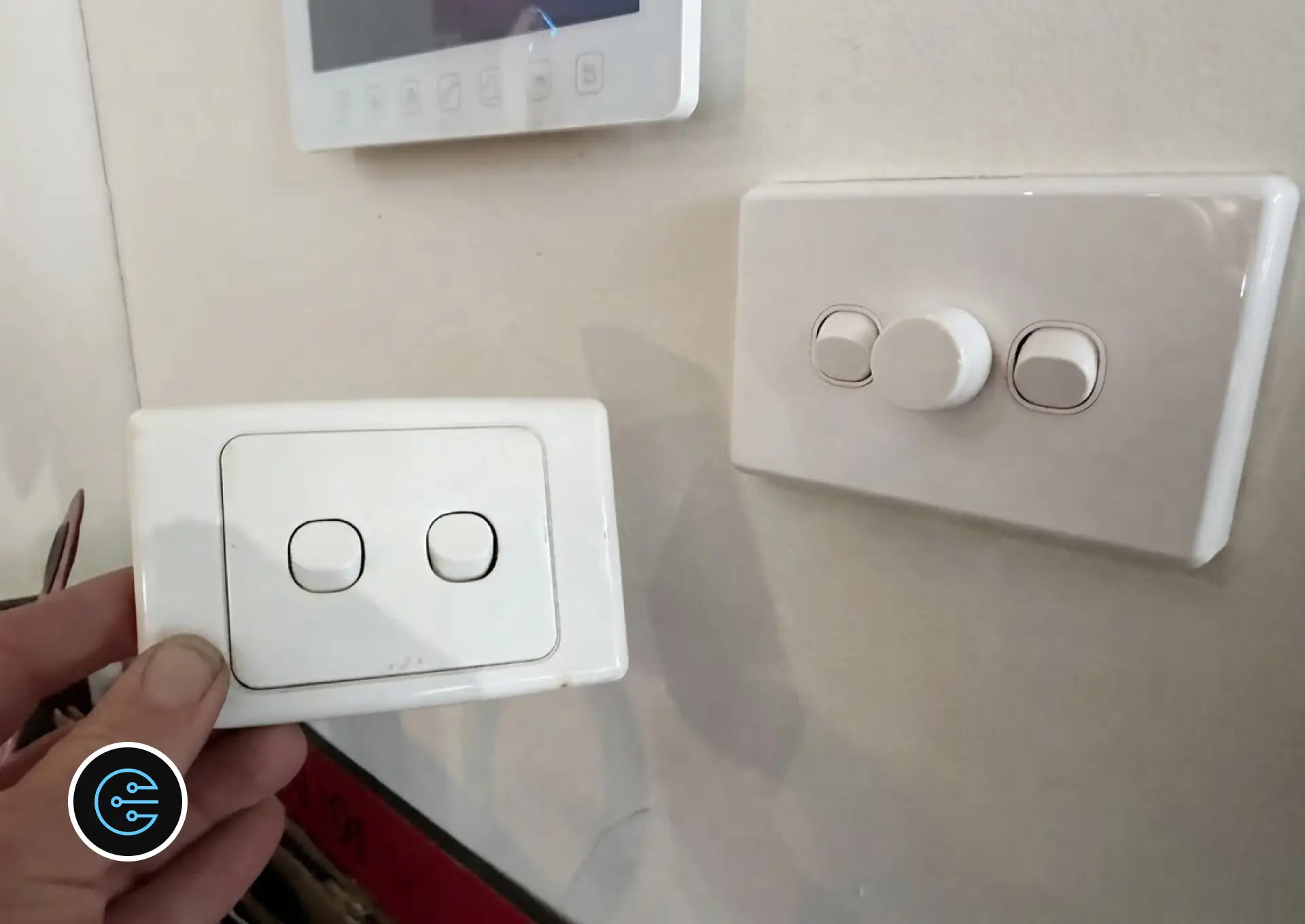 Old two-gang switch plate held next to the new dimmer and switch plate on the wall.