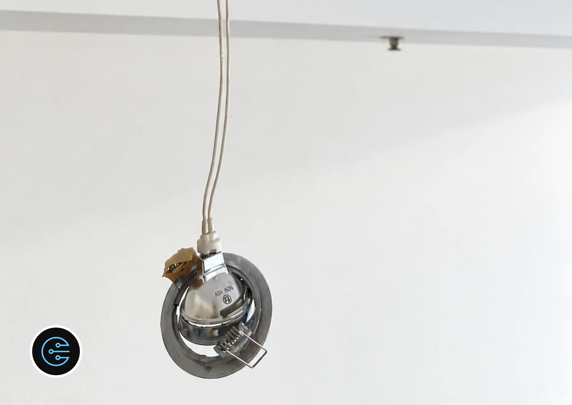 Old 50W 12 volt halogen downlight hanging from its wires after removal in Malvern